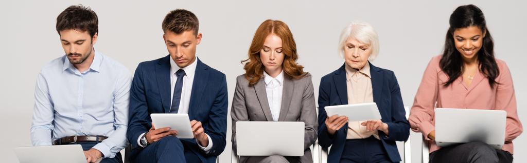 Multiethnic businesspeople using digital tablets and laptops isolated on grey, banner - Φωτογραφία, εικόνα