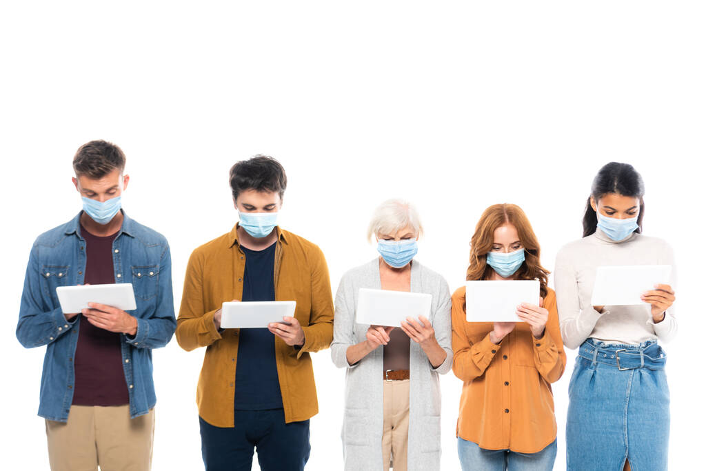 Wieloetniczni ludzie w maskach medycznych z użyciem cyfrowych tabletek wyizolowanych na białym tle - Zdjęcie, obraz