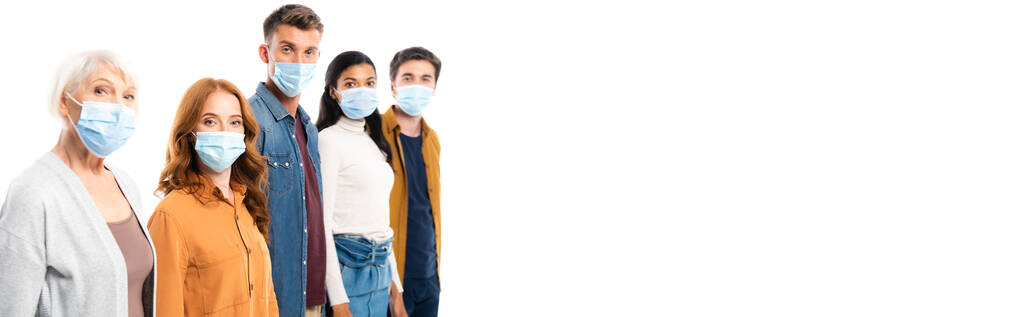 Young people in medical masks looking at camera near multiethnic friends isolated on white, banner  - Fotografie, Obrázek