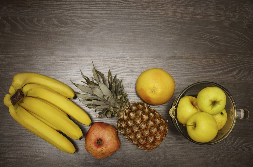 Pineapple, bananas and yellow apples on black wooden background. Tropical fruit.  ingredients for smoothie - Photo, Image