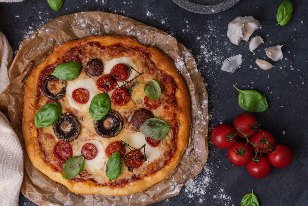 Uma vista superior de uma pizza com tomates, cogumelos e manjericão - Foto, Imagem
