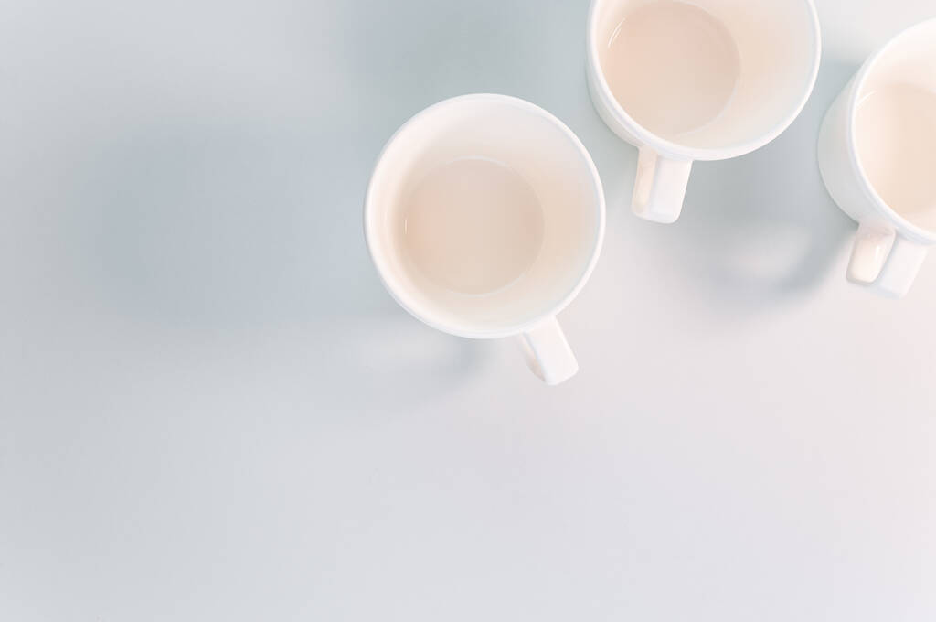 Una vista superior de tazas de café blanco vacías colocadas sobre una superficie blanca - Foto, imagen