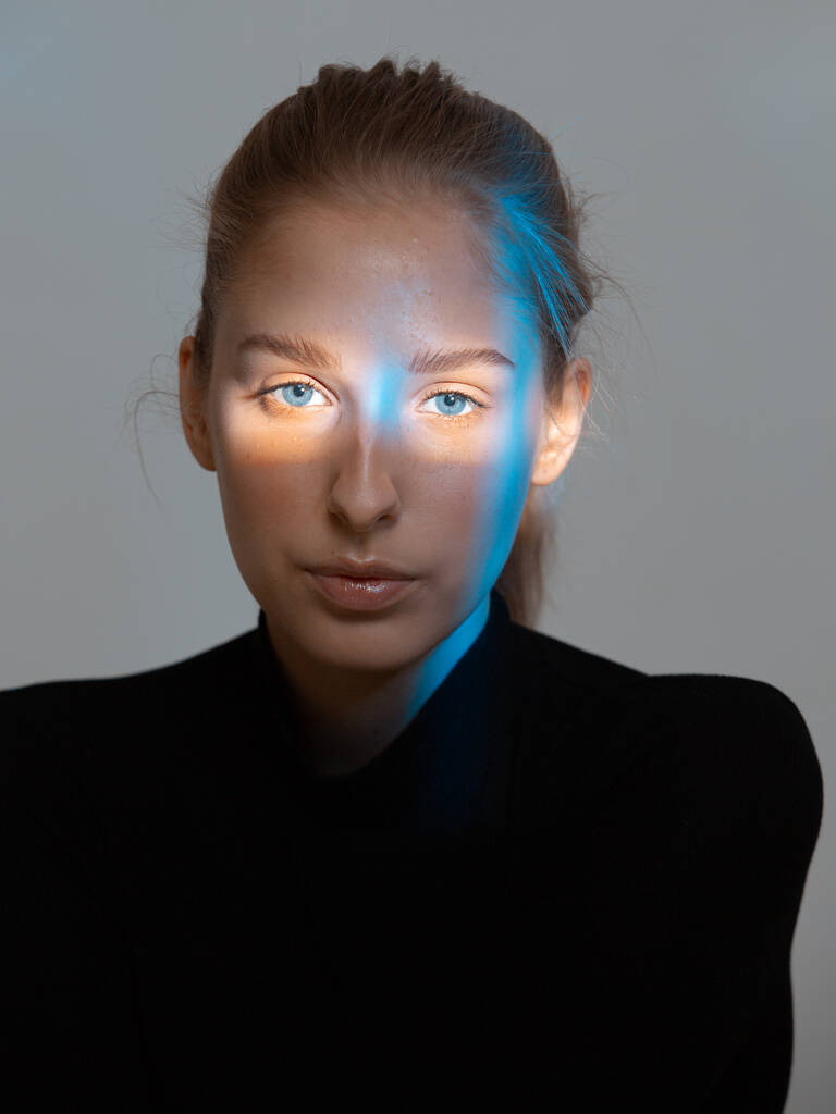 Piękna młoda kobieta z neonowym niebieskim światłem na twarzy - Zdjęcie, obraz