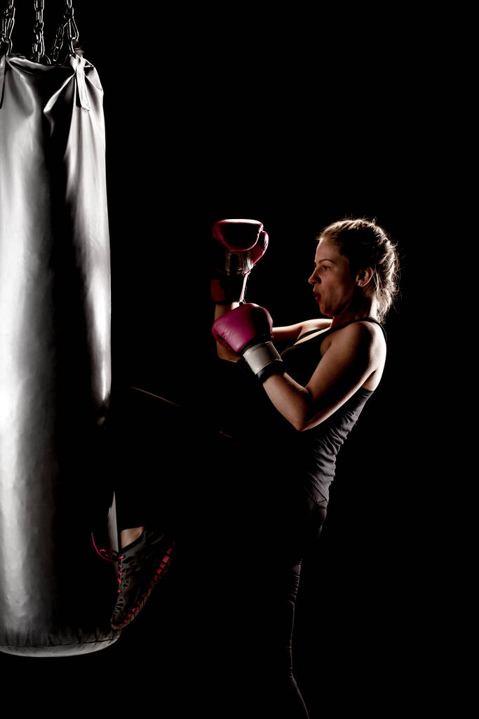 kick fighter dziewczyna uderzając w worek bokserski z jej nogi - Zdjęcie, obraz