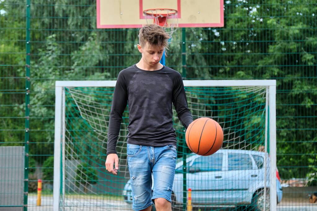 Outdoor portret van tiener jongen spelen straat basketbal - Foto, afbeelding