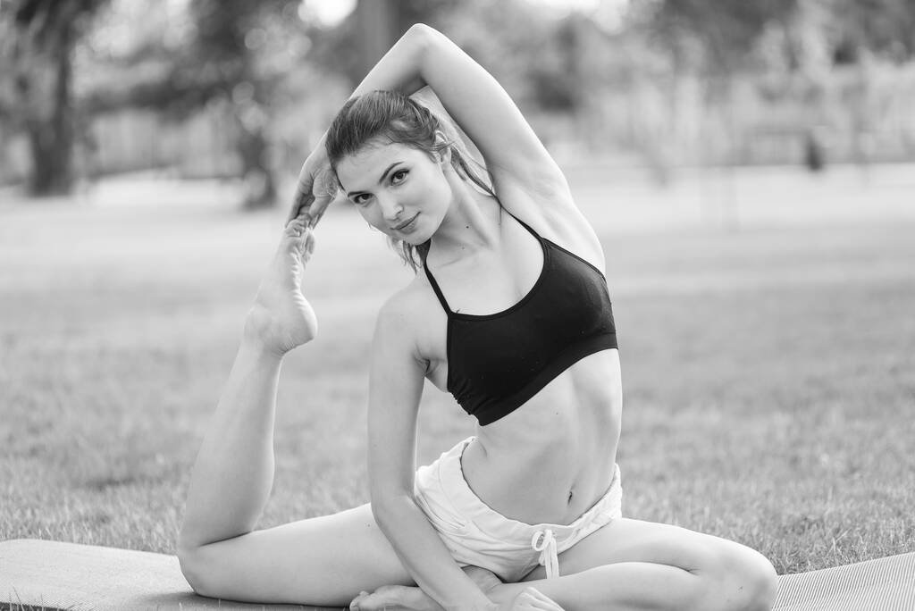 Chica haciendo yoga en el parque durante el día. Foto en blanco y negro. BW - Foto, imagen