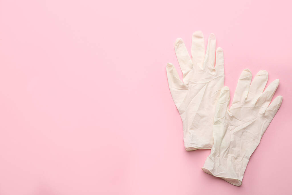 Een paar medische handschoenen op roze achtergrond, plat gelegd. Ruimte voor tekst - Foto, afbeelding