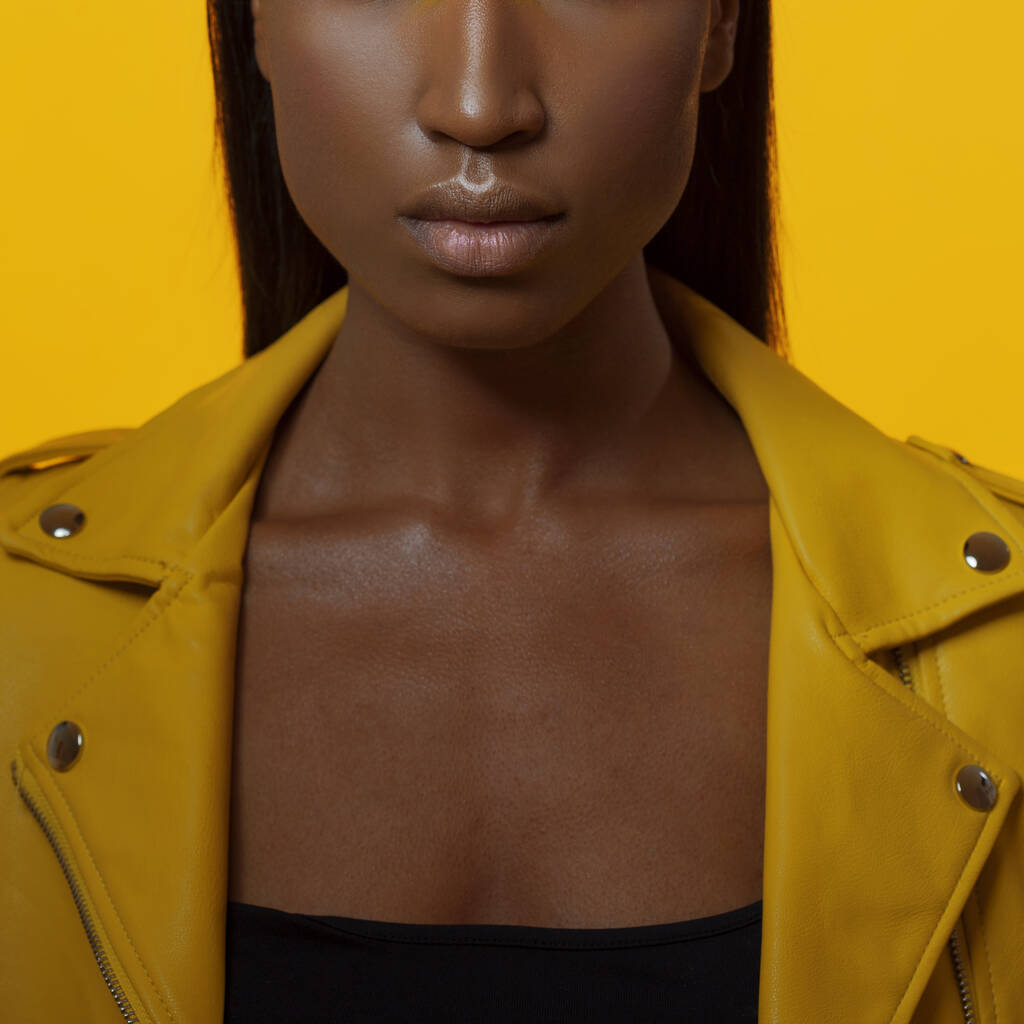 Heldere stijlvolle zwarte vrouw op een gele achtergrond in een geel leren jasje, - Foto, afbeelding