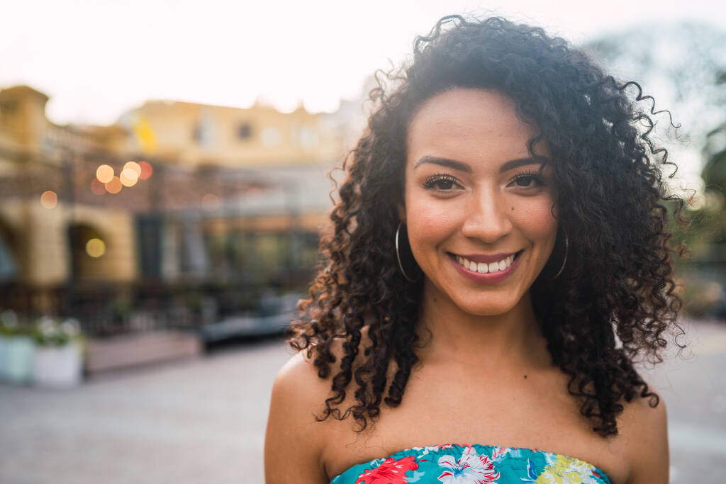 Retrato de una hermosa mujer latina afroamericana confiada riendo en la calle. Al aire libre. - Foto, imagen