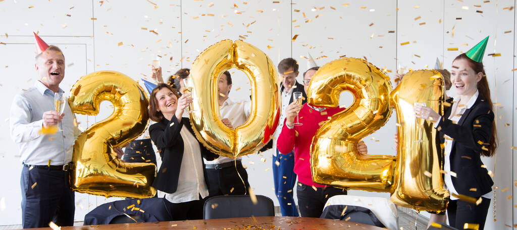 Business people are celebrating holiday in modern office drinking champagne and having fun in coworking. Merry Christmas and Happy New Year 2021. Balloon numbers - Photo, Image