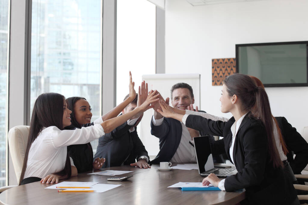 Feliz equipo de negocios haciendo cinco con sus manos en la oficina - Foto, imagen