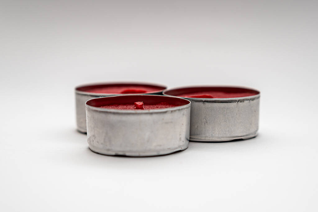 Een close-up shot van kleine decoratieve rode kaarsen in metalen koffers geïsoleerd op een witte achtergrond - Foto, afbeelding