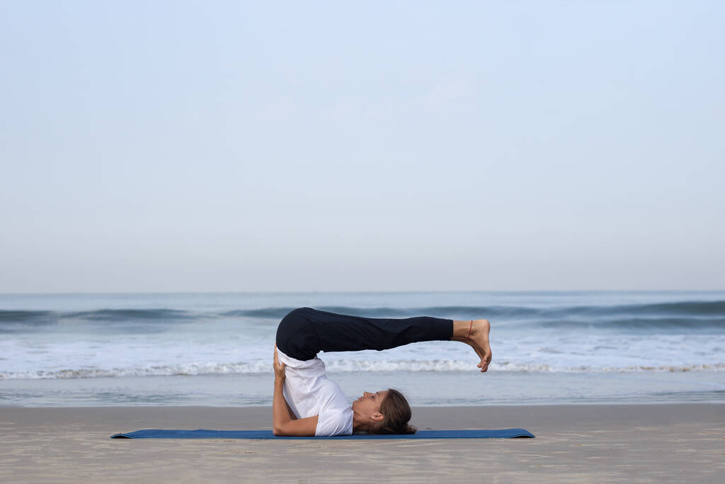 jovencita en la playa haciendo yoga. en ropa blanca - Foto, Imagen