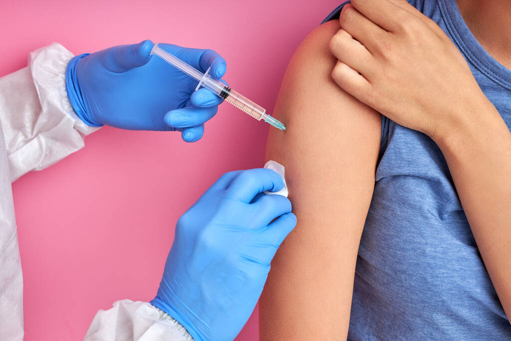 lähikuva lääkärin kädestä ruiskulla rokotteen antamiseksi aikuiselle naispotilaalle - Valokuva, kuva