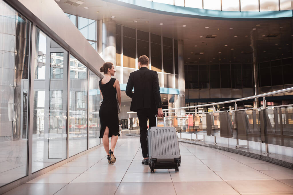 Γυναίκα και άντρας μεταφέρουν τη βαλίτσα τους στο αεροδρόμιο. - Φωτογραφία, εικόνα