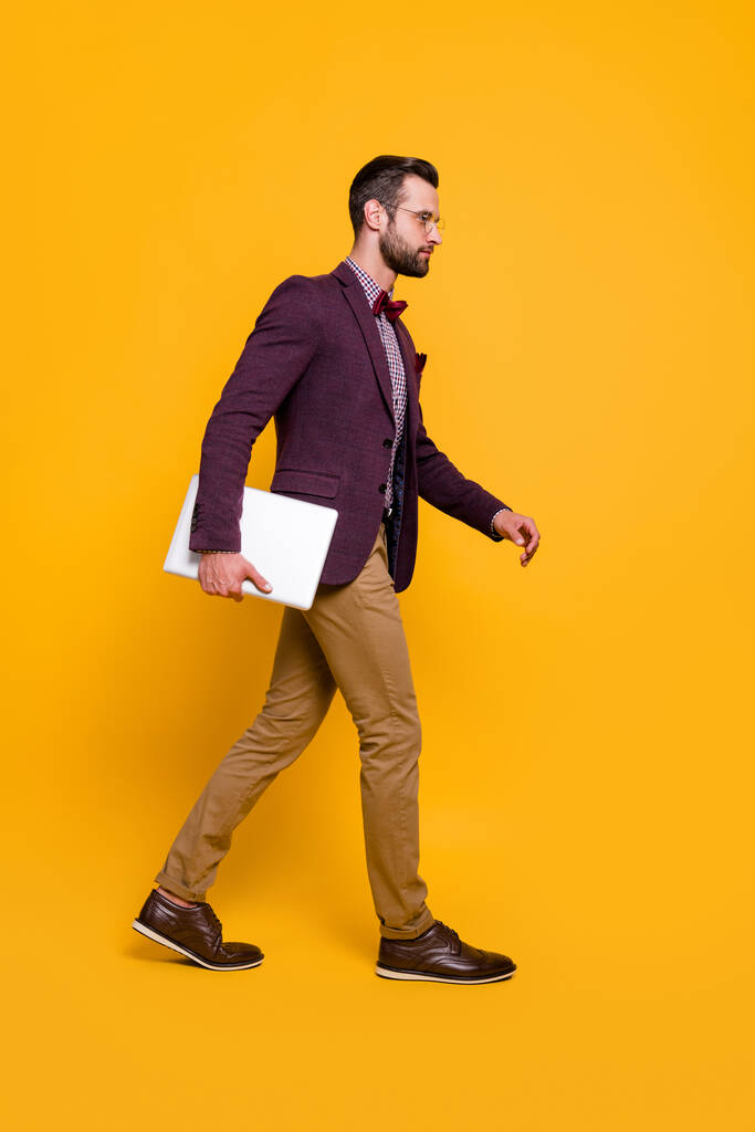 Vertical full length body size view of his he nice attractive serious guy going carrying laptop working remotely digital project start-up isolated on bright vivid shine vibrant yellow color background - Photo, Image
