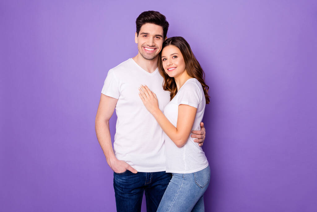 Фото двух милых людей в белых футболках, обнимающих изолированный фиолетовый цвет фона - Фото, изображение