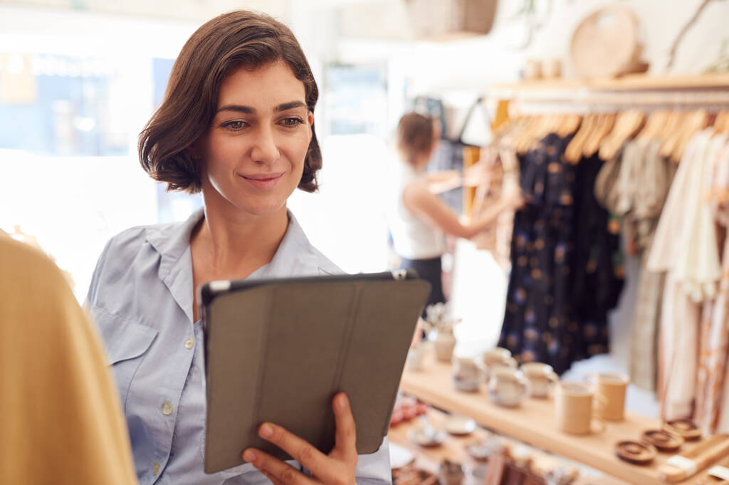 Kobieta Właścicielka sklepu z modą za pomocą tabletu cyfrowego, aby sprawdzić zapasy na szynach w sklepie odzieżowym - Zdjęcie, obraz