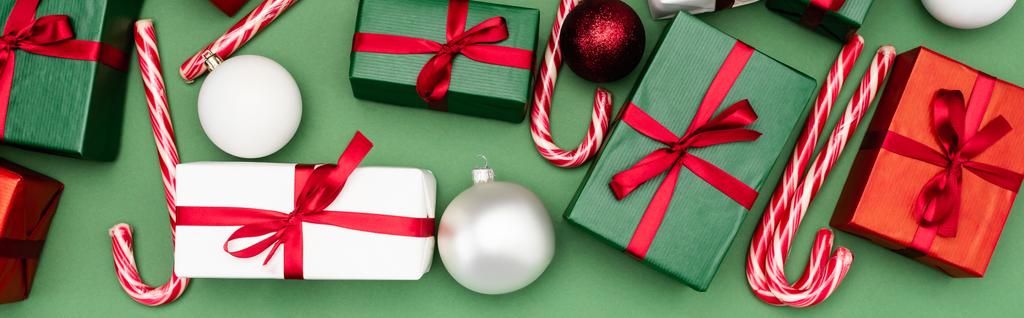 Renkli hediye kutularının panoramik konsepti, baston şekerler ve yeşil arka planda noel topları, üst manzara - Fotoğraf, Görsel