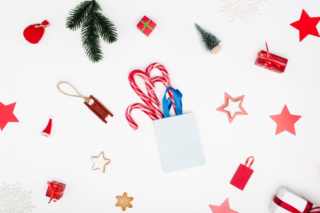 Noel arkaplanda şeker kamışları ve beyaz arka planda kurabiyeler olan bir alışveriş çantası. - Fotoğraf, Görsel