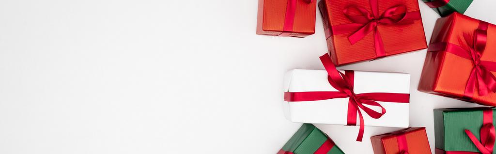 concepto horizontal de coloridas cajas de regalo con cintas rojas sobre fondo blanco, vista superior - Foto, imagen