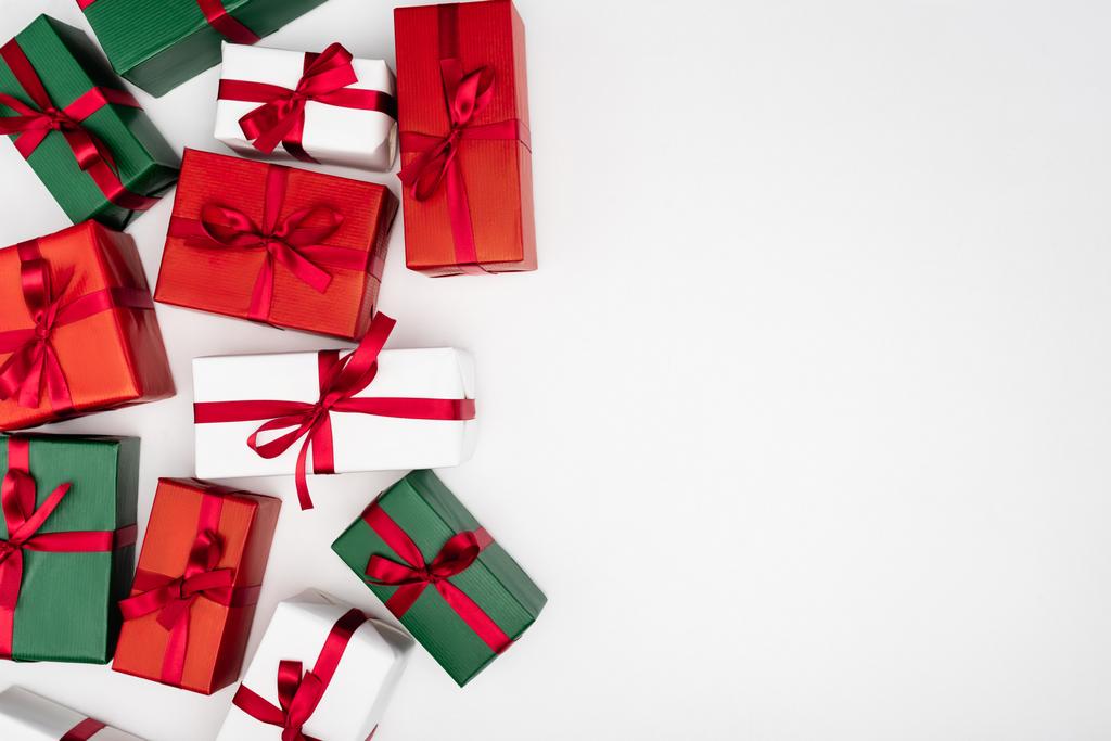 Draufsicht auf bunte Geschenkboxen mit roten Bändern auf weißem Hintergrund mit Kopierraum - Foto, Bild
