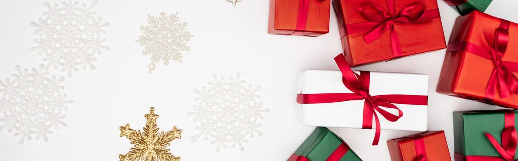 concepto panorámico de cajas de regalo multicolores y copos de nieve decorativos sobre fondo blanco - Foto, Imagen