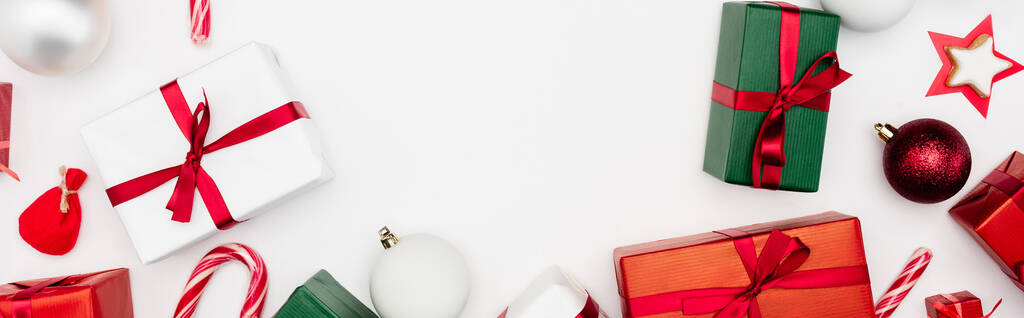 panoramatický záběr dárkových krabic, vánočních míčků a cukrovinek na bílém pozadí - Fotografie, Obrázek