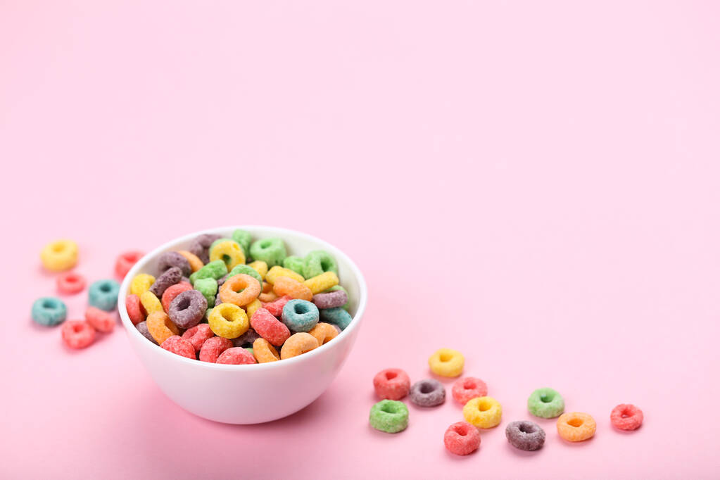Цветные кукурузные кольца в миске на розовом фоне - Фото, изображение