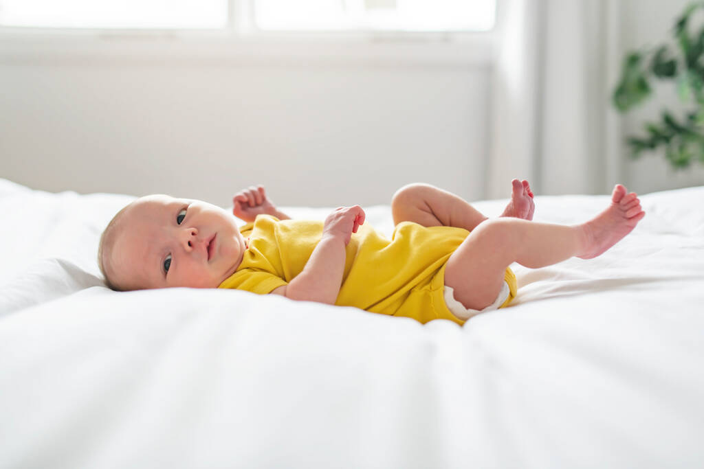 Χαριτωμένο νεογέννητο κοριτσάκι στο λευκό κρεβάτι - Φωτογραφία, εικόνα