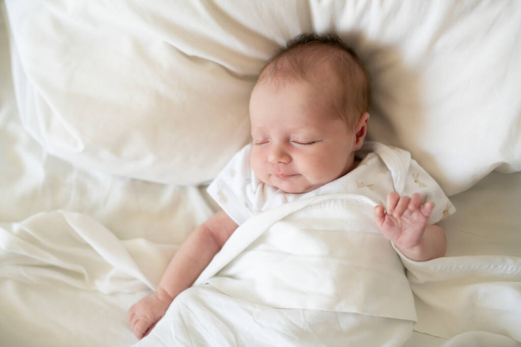 Egy édes újszülött lány, aki fehér ágyban alszik - Fotó, kép