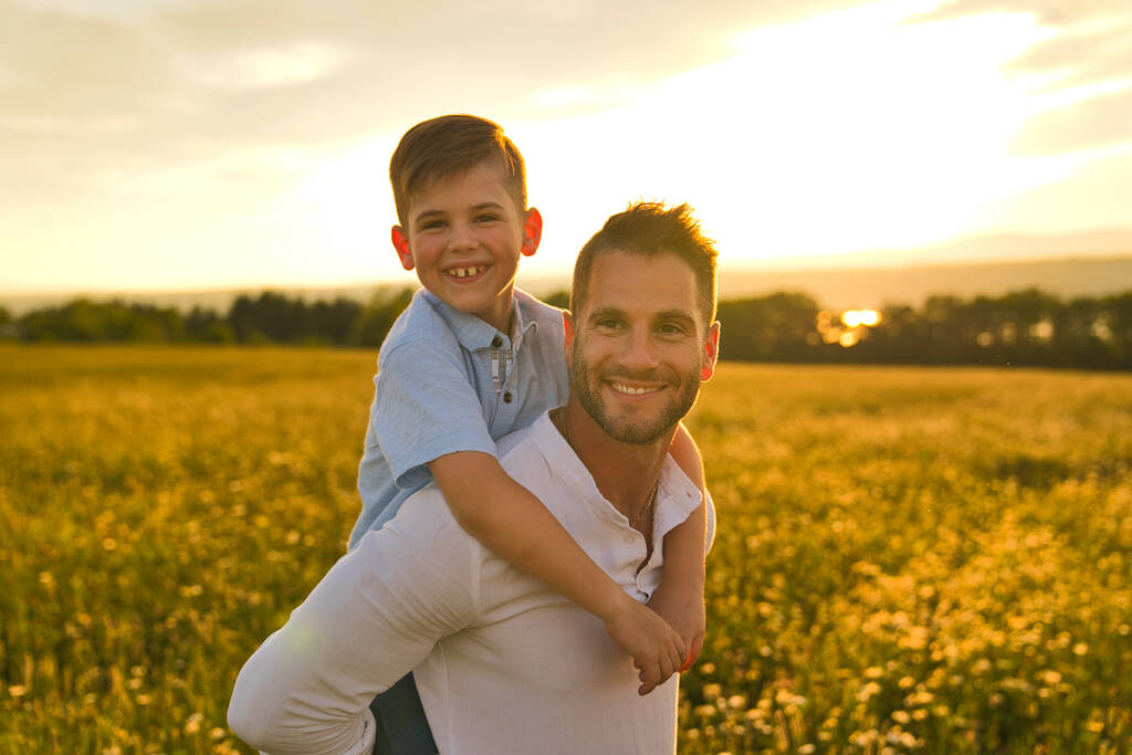 felice famiglia di padre e figlio sul campo al tramonto divertendosi - Foto, immagini