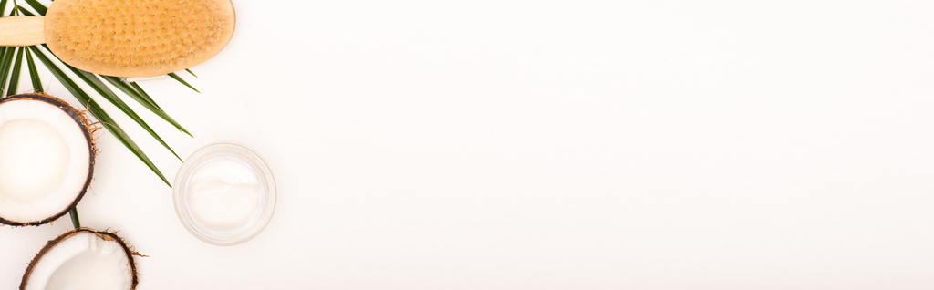 καρύδα μισά, βούρτσα μασάζ, καλλυντική κρέμα και φύλλα φοίνικα σε λευκό με χώρο αντίγραφο, πανό - Φωτογραφία, εικόνα