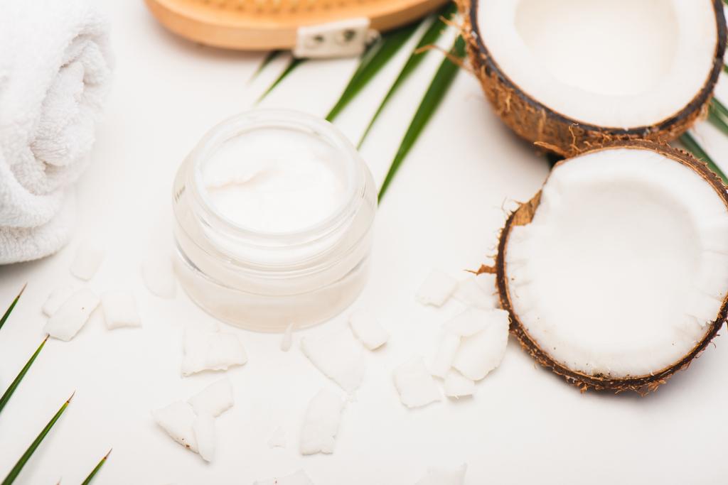 coconut halves, flakes, container with cosmetic cream and towel on white background - Photo, Image