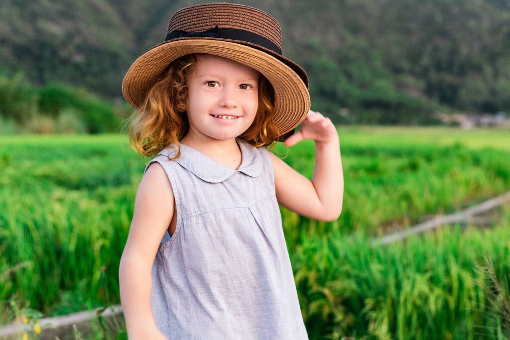 Child girl in straw hat. Cute kid looking at nature lanscape background. Adventure travel concept in retro style - Photo, Image