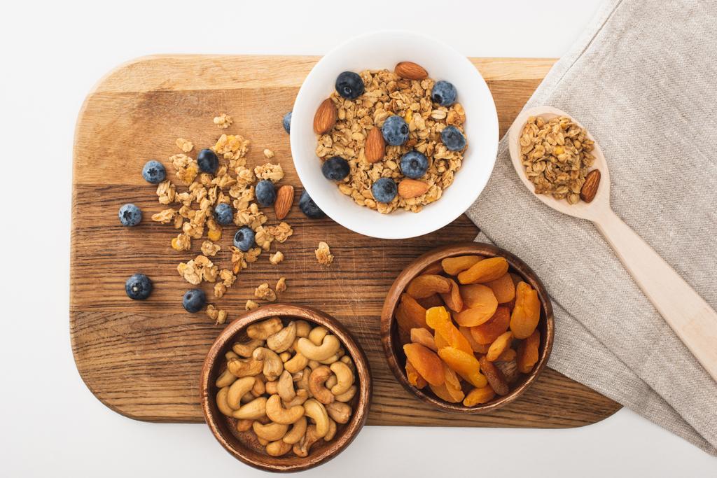 vue de dessus de délicieux granola aux noix, bleuets et abricots secs isolés sur blanc - Photo, image