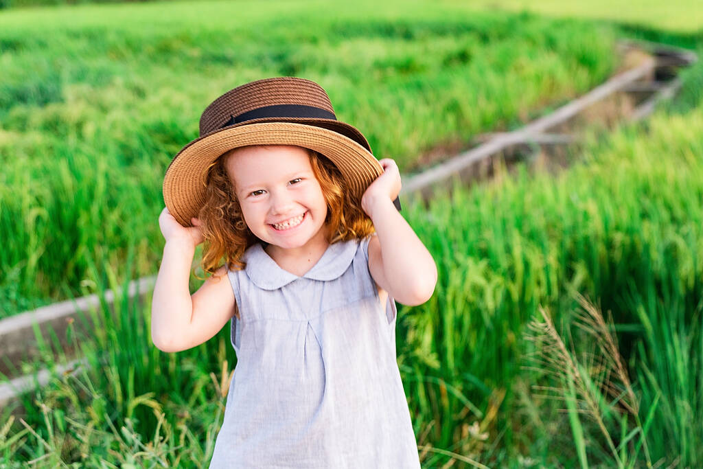 Dziewczynka w słomkowym kapeluszu. Słodki dzieciak patrzący na środowisko naturalne. Pojęcie podróży przygodowej w stylu retro - Zdjęcie, obraz