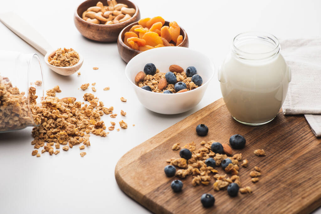 vynikající granola s jogurtem, ořechy, sušené meruňky a borůvky na bílém pozadí - Fotografie, Obrázek
