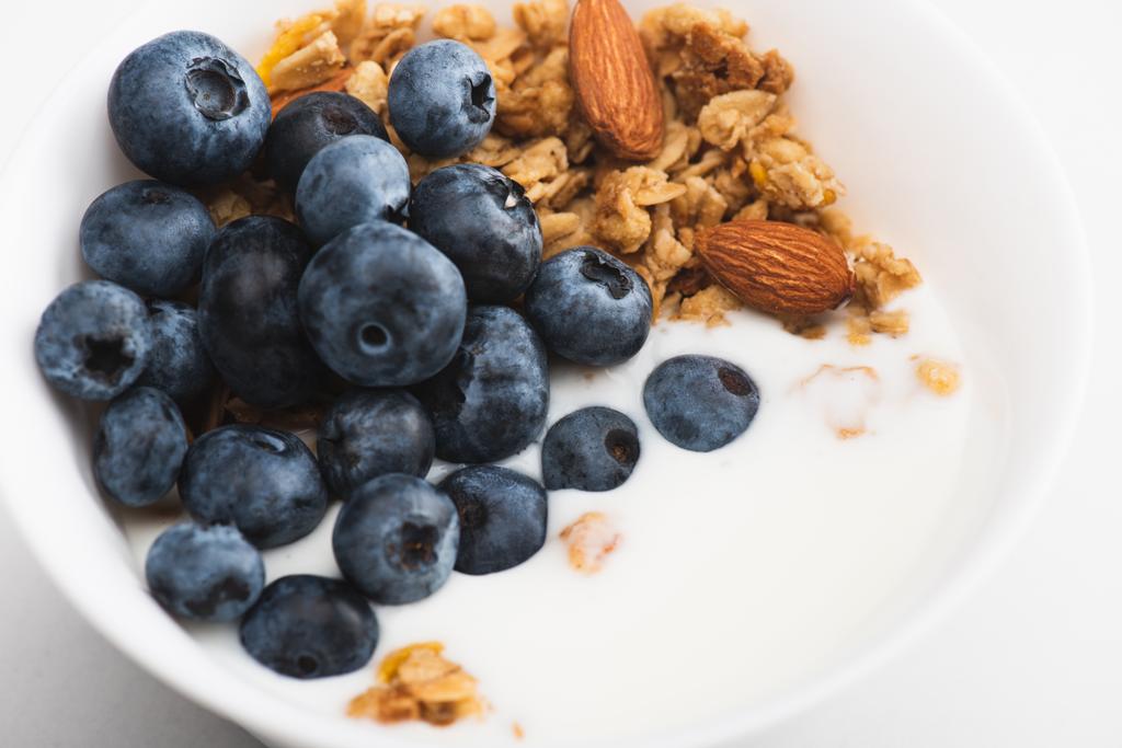 detailní záběr lahodné granoly s oříšky, jogurtem, borůvkou v misce - Fotografie, Obrázek