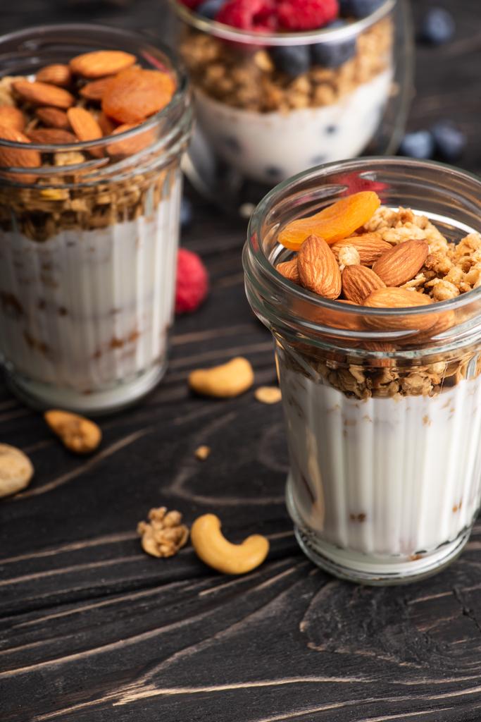 delicious granola with dried apricots, nuts and yogurt in glass cup on blurred background - Photo, Image
