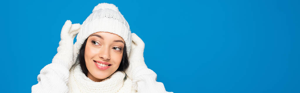 szczęśliwa kobieta w białym stroju zimowym patrząc odizolowany na niebieskim, sztandar - Zdjęcie, obraz