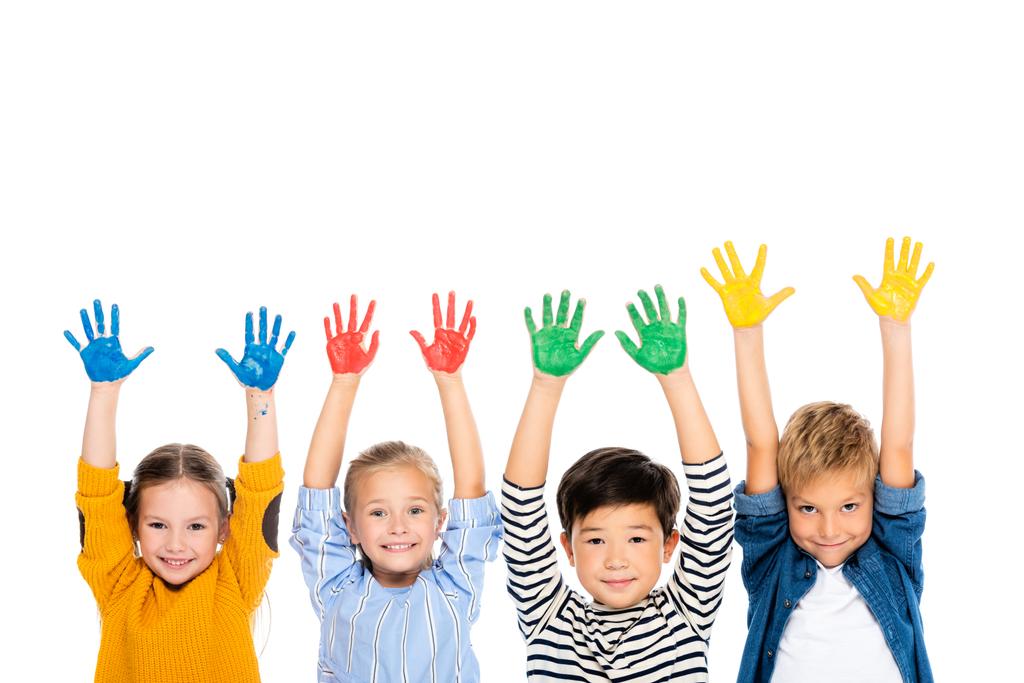Allegro bambini multietnici con le mani in vernice colorata guardando la fotocamera isolata su bianco - Foto, immagini