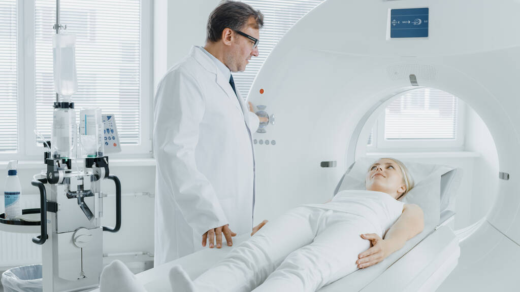 En laboratoire médical Radiologiste Contrôles IRM ou CT ou PET Scan avec patiente subissant une procédure. Équipement médical moderne de haute technologie. Chats de médecin amical avec patient. - Photo, image