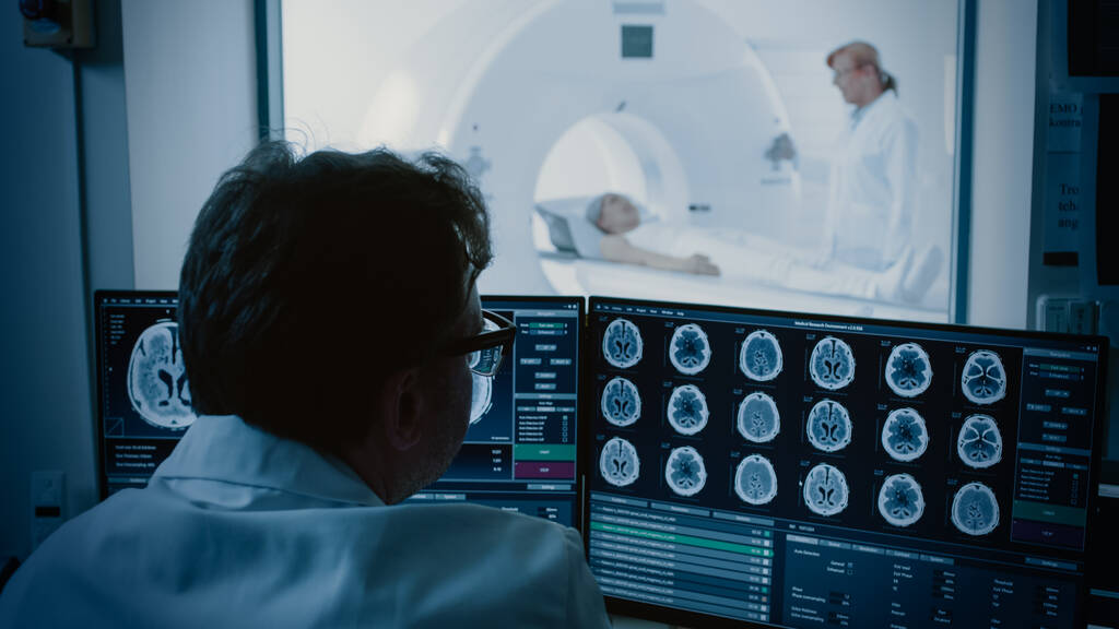 Nel laboratorio medico paziente viene sottoposto a risonanza magnetica o CT processo di scansione sotto la supervisione di radiologo, in sala di controllo medico Orologi Procedura e monitor Attività cerebrale. - Foto, immagini