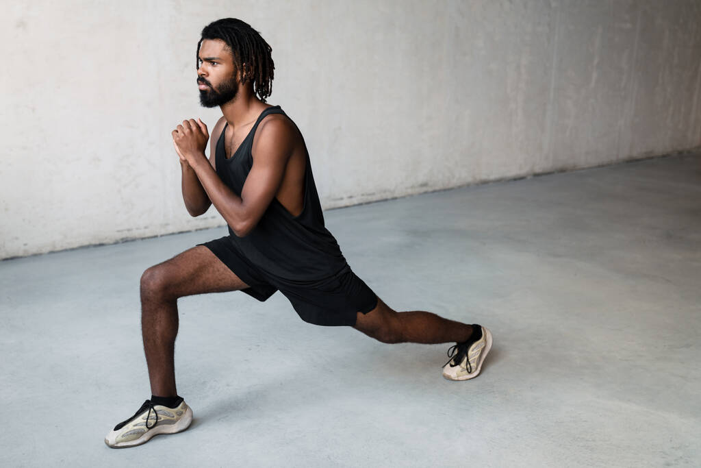 Immagine di un giovane sportivo afroamericano che fa esercizio mentre si allena in casa - Foto, immagini