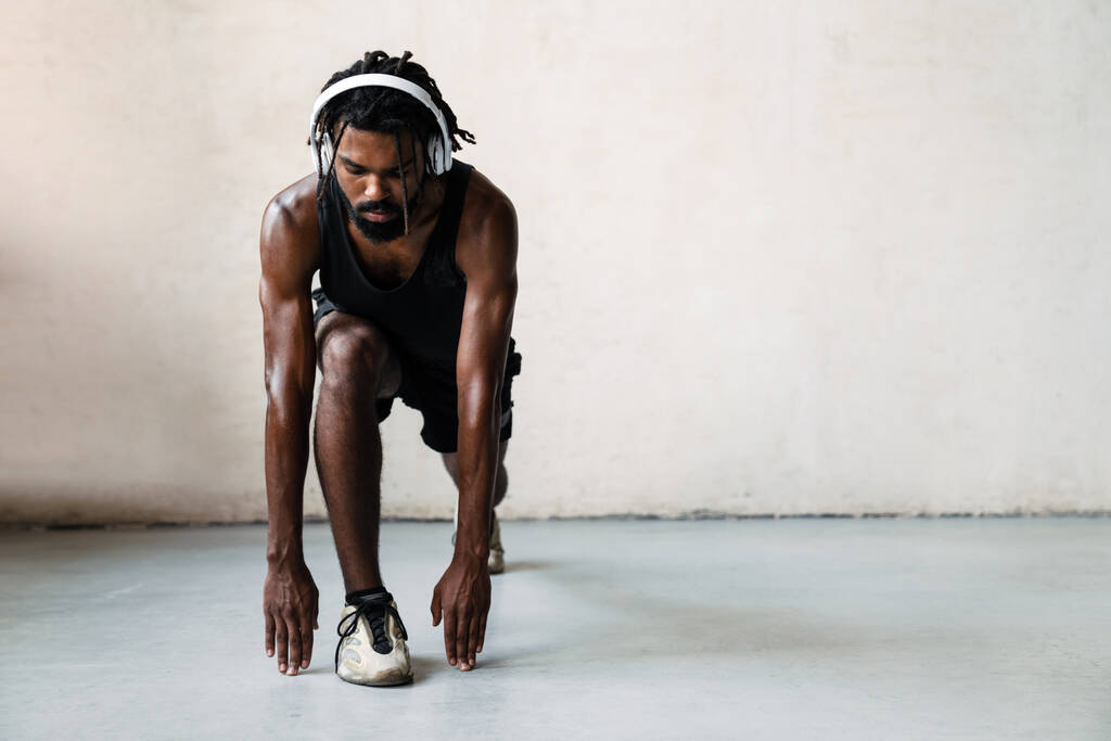Kép a sportos afro-amerikai sportoló a fejhallgató gyakorló, miközben dolgozik ki beltéri - Fotó, kép
