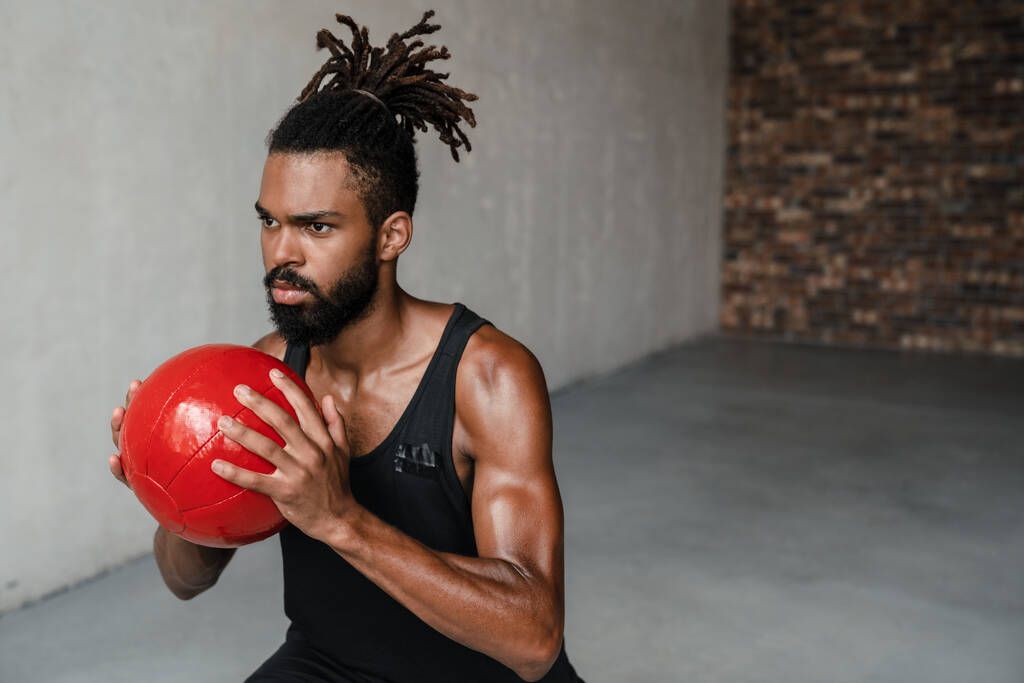 Imagen de atlético afroamericano deportista haciendo ejercicio con balón de medicina en interiores - Foto, imagen
