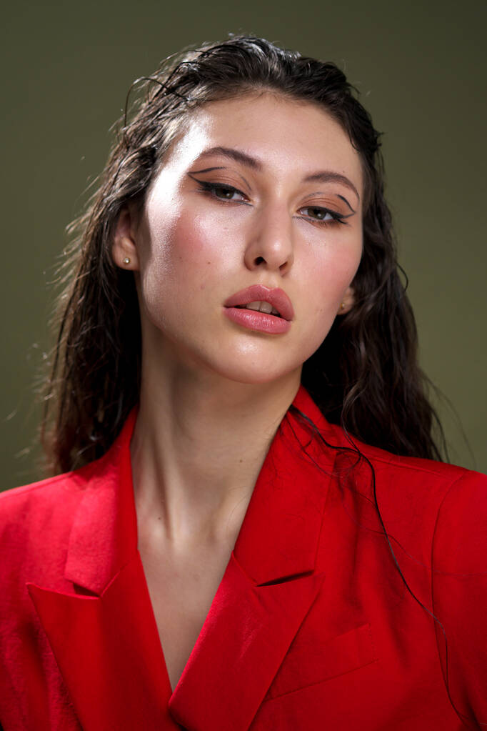 Kırmızı ceketli şehvetli bir genç kadın portresi. Stüdyodaki yeşil arka planda ıslak, uzun siyah saçlı.. - Fotoğraf, Görsel