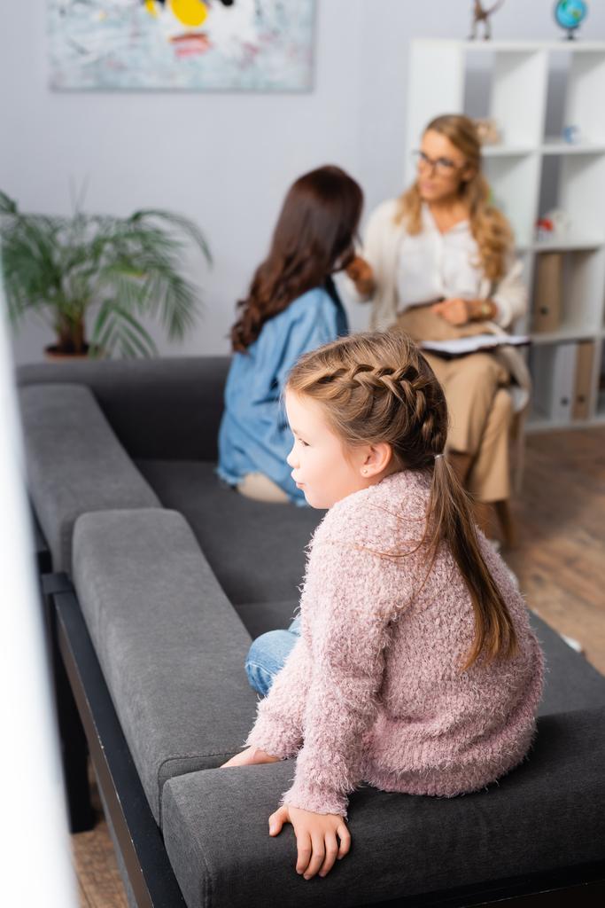 дочь сидит на диване, пока мама разговаривает с психологом - Фото, изображение