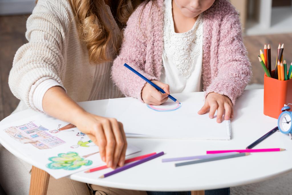 περικοπή άποψη του μικρού κοριτσιού ζωγραφίζει εικόνες με πολύχρωμα μολύβια, ενώ επισκέπτονται ψυχολόγο - Φωτογραφία, εικόνα